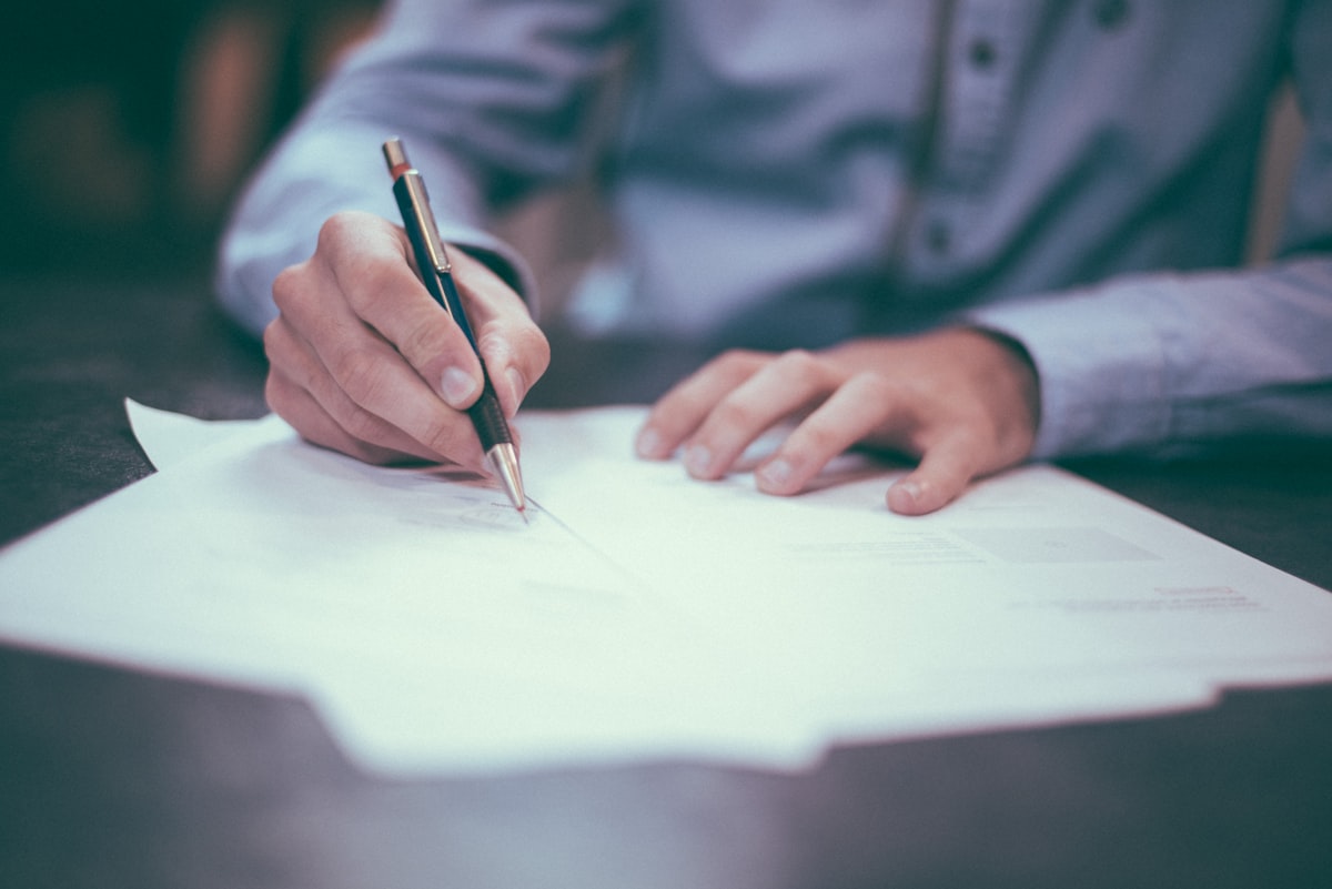 A hand working through a printed report with a pen